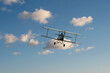 biplane plane in the blue sky with white clouds