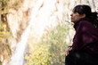© carles - Profile of a woman sitting while looking at a small waterfall in the forest
