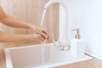 Wall Mural - Washing hands under the flowing water tap. Hygiene concept hand detail. Washing hands rubbing with soap for corona virus prevention, hygiene to stop spreading corona virus in or public wash room.