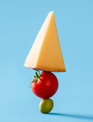 Swiss cheese with tomato and green olive isolated on blue background.