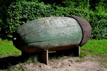 Wall Mural - A close up on a massive figurine located in the middle of a public park next to some shrubs that resembles a big yellow nut or acron with a brown cap seen on a sunny summer day on a Polish countryside