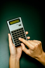 Female Hands Using A Scientific Calculator On Dark Background (Green Tone)