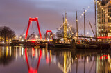 Fototapeta Londyn - Rotterdam, The Netherlands, January 7, 2022: early morning at the Old Harbour, with historic barges, Willems bridge and the facade of the White House
