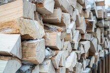 Close-up Of Firewood In Storage Or In A Barn Covered With Snow. Stock Of Wooden Logs In The Street. Chopped Wood For Fireplace. Logging In The Countryside Or Out Of Town.