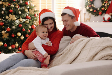 Wall Mural - Happy couple with cute baby on sofa in room decorated for Christmas