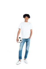 Wall Mural - happy african american man standing with hand in pocket while holding soccer ball on white.