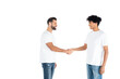 © LIGHTFIELD STUDIOS - happy interracial men in t-shirts and jeans looking at each other and shaking hands isolated on white.