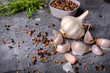 Garlic, spices and fresh herbs on black stone background, blackboard. Culinary concept, horizontal view.