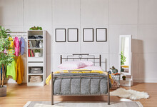 Metal Bedstead In The Bed Room, White Wall Background, Frame, Wardrobe, Clothes And Blanket Style.