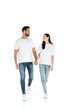 © LIGHTFIELD STUDIOS - full length view of happy interracial couple looking at each other and holding hands while walking on white.