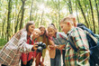 © standret - Holding camera. Kids in green forest at summer daytime together