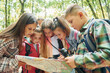© standret - Using map. Kids in green forest at summer daytime together