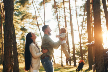 Having a walk. Happy family of father, mother and little daughter is in the forest