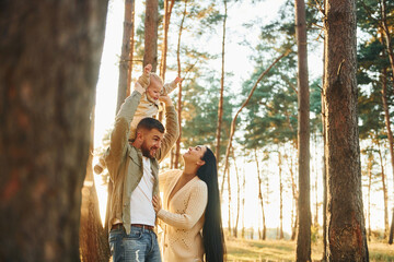 Joy and happiness. Family of father, mother and little daughter is in the forest