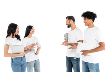 Wall Mural - smiling multiethnic friends with laptops pointing at each other while talking isolated on white.