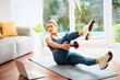 © gzorgz - Shot of a middle aged woman using laptop while exercising at home