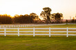 © Austockphoto - White post and rail plastic fencing in paddock of mown grass