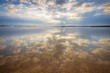 © Austockphoto - Ground level view of reflections of a dramatic sunset sky on a wet sandy beach