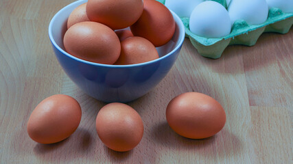 Poster - several fresh chicken eggs in a ceramic cup on a wooden background. Healthy eating concept