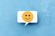 A yellow happy smiley face on a callout for text on a blue background. The concept of mood selection and customer feedback. Copy space