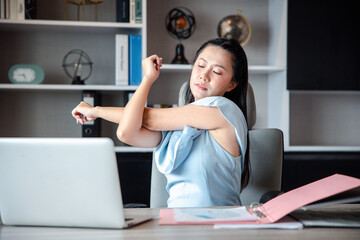 A businesswoman who works in the office looks tired and stressed by pressing her hands