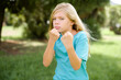 © Roquillo - Caucasian little kid girl wearing blue T-shirt standing outdoors Ready to fight with fist defense gesture, angry and upset face, afraid of problem.