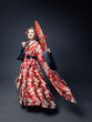 Beautiful young woman in red traditional Chinese costume dancing with umbrella