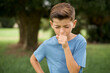 Caucasian little kid boy wearing blue T-shirt standing outdoor feeling unwell and coughing as symptom for cold or bronchitis. Healthcare concept.