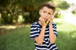 © Roquillo - Afraid funny beautiful Caucasian little kid boy wearing stripped T-shirt standing outdoors holding telephone and bitting nails