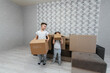 © Andrii - Brothers and sister are playing and enjoying moving to a new apartment against the background of cardboard boxes and a sofa. Purchase of real estate. Housewarming, delivery.