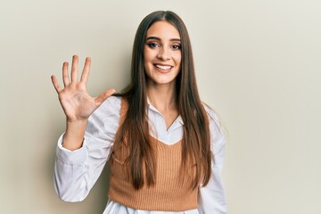 Wall Mural - Beautiful brunette young woman wearing casual clothes showing and pointing up with fingers number five while smiling confident and happy.