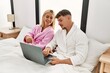 © Krakenimages.com - Young caucasian couple smiling happy using laptop sitting on the bed at home.