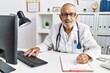 © Krakenimages.com - Senior grey-haired man wearing doctor uniform working at clinic