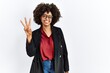 © Krakenimages.com - African american woman with afro hair wearing business jacket and glasses showing and pointing up with fingers number three while smiling confident and happy.