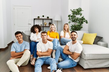 Poster - Group of people sitting on the sofa and floor at home happy face smiling with crossed arms looking at the camera. positive person.