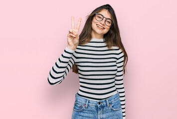 Canvas Print - Young beautiful teen girl wearing casual clothes and glasses showing and pointing up with fingers number two while smiling confident and happy.