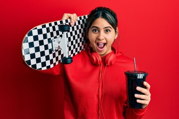 Poster - Young latin woman holding skate drinking soda celebrating crazy and amazed for success with open eyes screaming excited.