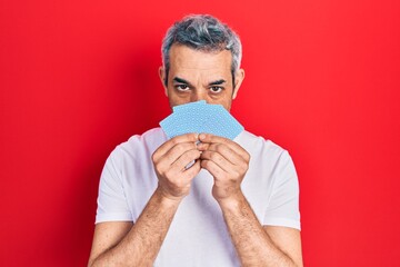 Sticker - Handsome middle age man with grey hair covering face with cards relaxed with serious expression on face. simple and natural looking at the camera.