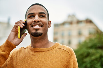 Wall Mural - Young african american man smiling happy talking on the smartphone at the city.