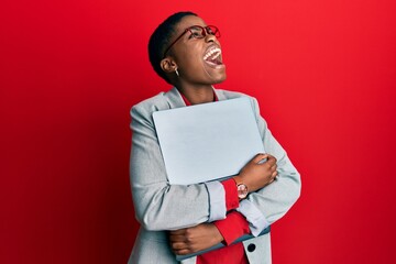 Sticker - Young african american businesswoman holding laptop angry and mad screaming frustrated and furious, shouting with anger looking up.