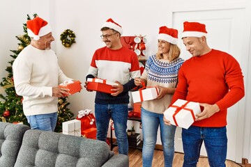 Sticker - Group of middle age friends holding gifts standing by christmas tree at home.