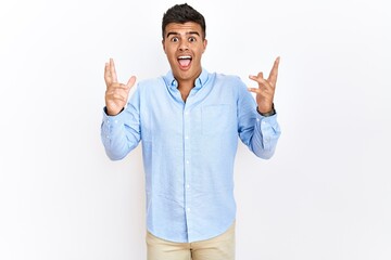 Poster - Young hispanic man wearing business shirt standing over isolated background celebrating crazy and amazed for success with arms raised and open eyes screaming excited. winner concept