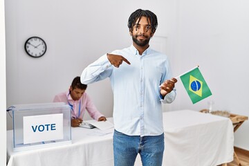 Wall Mural - Young hispanic men at political campaign election holding brazil flag pointing finger to one self smiling happy and proud