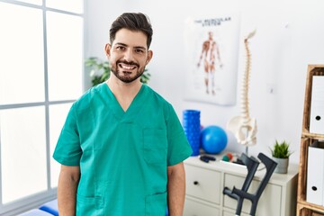 Poster - Young man with beard working at pain recovery clinic with a happy and cool smile on face. lucky person.