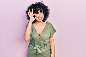 Young middle east woman wearing casual clothes smiling positive doing ok sign with hand and fingers. successful expression.