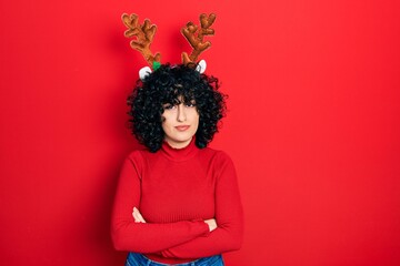 Sticker - Young middle east woman wearing cute christmas reindeer horns skeptic and nervous, disapproving expression on face with crossed arms. negative person.