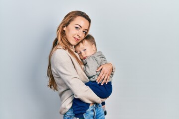 Young caucasian woman holding and hugging her son with love. Family of two bonding together. Mother holding infant toddler