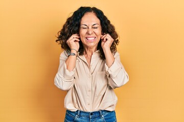 Poster - Middle age hispanic woman wearing casual clothes covering ears with fingers with annoyed expression for the noise of loud music. deaf concept.