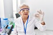 © Krakenimages.com - Senior grey-haired woman wearing scientist uniform holding pill at laboratory