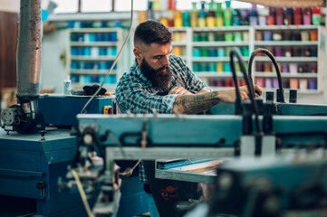 Wall Mural - Male worker using printing machine in a workshop